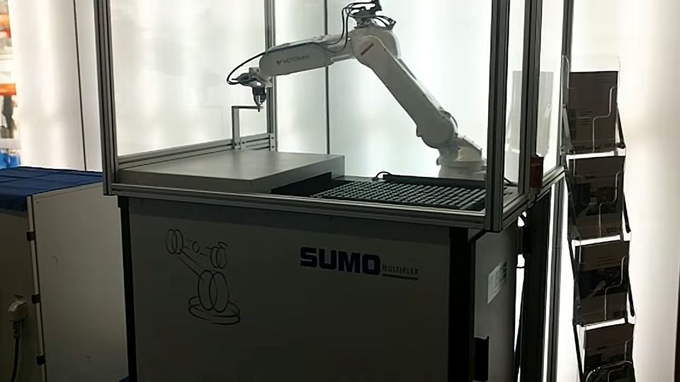 Weißer Roboterarm be- und entladet Werkstücke